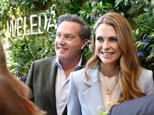 Madeleine och Chris ler glatt framför en grönskande vägg med texten "WELEDA".