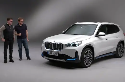 Dwóch mężczyzn stoi obok białego BMW iX1.
