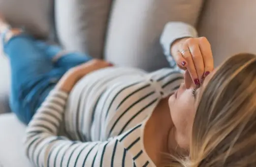 Kobieta w ciąży leży na kanapie, dotykając czoła. Zmartwienie o brak bicia serca w 8 tygodniu ciąży maluje się na jej twarzy.