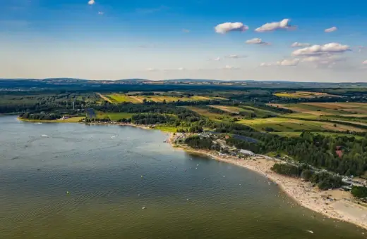 Letnie słońce nad **Jeziorem Chańcza**. Tłumy plażowiczów, zielone lasy i pola tworzą malowniczy krajobraz.