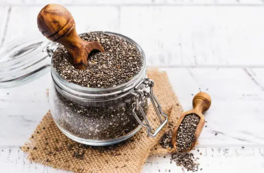 Słoik pełen nasion chia, idealnych dla kobiet w ciąży, z drewnianą łyżką. Nasiona chia to bogactwo kwasów omega-3 i błonnika.