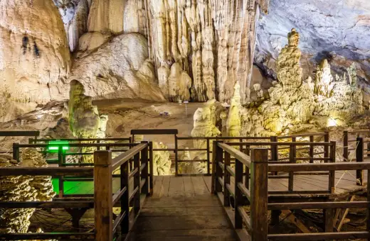 Drewniana kładka prowadzi przez wnętrze jaskini z imponującymi stalaktytami i stalagmitami, przypominającymi krajobraz najdłuższej jaskini w Polsce.