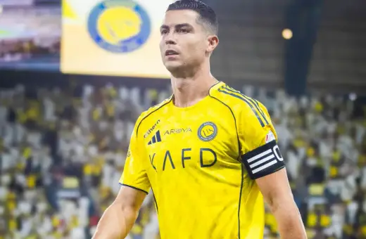Cristiano Ronaldo w żółtej koszulce Al Nassr, z opaską kapitana na ramieniu, na tle trybun pełnych kibiców.