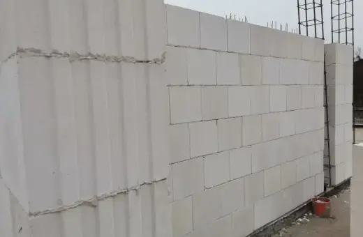 Ściana z bloczków silikatowych wznoszona na budowie. Widać zbrojenie i fragmenty fundamentów.