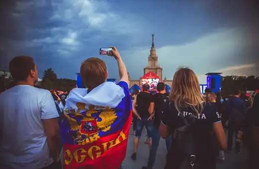 Fani w moskiewskim klubie piłkarskim, jeden z nich z flagą Rosji, nagrywa telefonem koncert.
