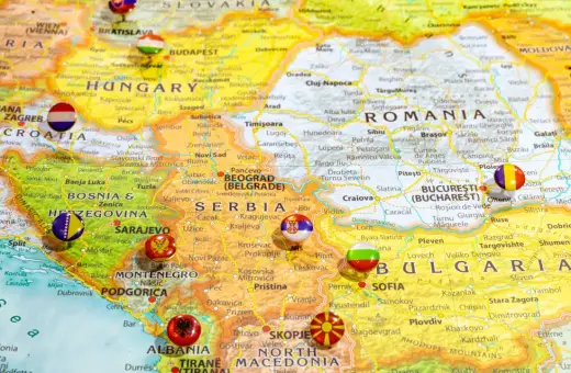 Mapa Europy z zaznaczonymi krajami bałkańskimi, w tym Serbią, Bułgarią i Rumunią, z flagami narodowymi w miejscach stolic.