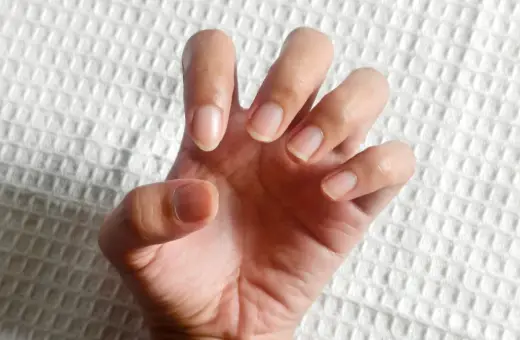 Dłoń z naturalnymi paznokciami, lekko zgięta, jakby chciała powiedzieć "hold my hand". Tło białe, fakturowane.