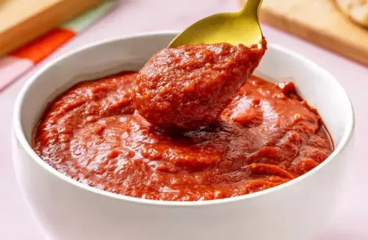 Gęsty, aromatyczny sos pelati nabierany złotą łyżką z białej miseczki. Idealny do makaronu i pizzy.
