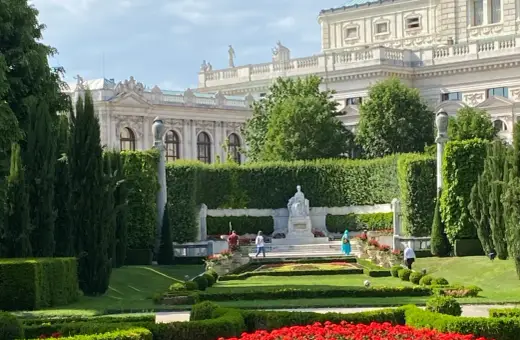 Wiedeń co zobaczyć: piękny ogród z rzeźbą i architekturą w tle.