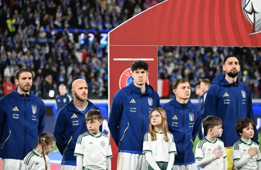 Piłkarze Włoch i Serbii stoją w rzędzie, dzieci w strojach kibicują.