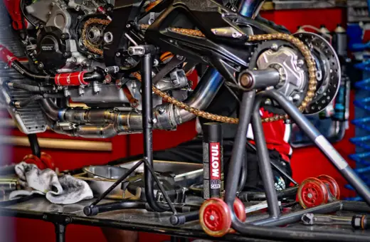 Motocykl na stojaku, gotowy do smarowania łańcucha. Puszka smaru Motul obok.