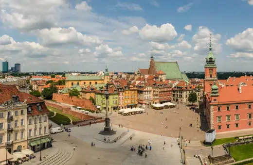 Uroczy city break z Warszawy. Rynek Starego Miasta tętni życiem, z kolorowymi kamieniczkami i Zamkiem Królewskim w tle.