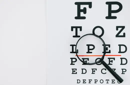 Tablica optometryczna z lupą, która powiększa literę "P". Może to symbolizować problemy ze wzrokiem, jak astygmatyzm nabyty.