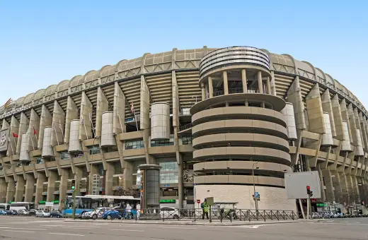 Imponujący stadion Realu Madryt, Santiago Bernabéu, z charakterystyczną betonową fasadą i okrągłą wieżą.