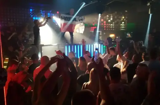 Tłum na parkiecie klubu, DJ na scenie z flagą Polski, światła i energia prawdziwego rave.