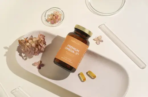 Suplement Omega-3 z DHA dla kobiet w ciąży, wspierający rozwój mózgu dziecka. Delikatne kapsułki na białej tacy z suszonymi kwiatami.