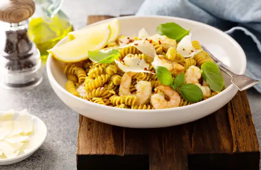 Pyszny makaron z ciecierzycy z krewetkami, cytryną i parmezanem, udekorowany bazylią.