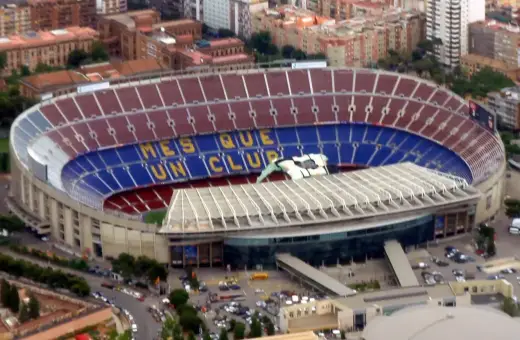 Camp Nou, z imponującą pojemnością, wita kibiców. Na trybunach widnieje napis "Més que un club".