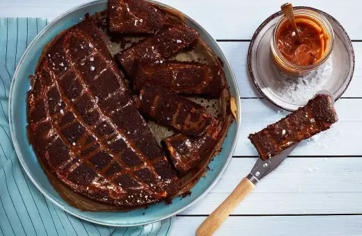 Chokladkaka med kolasås och havssalt, perfekt att baka glutenfritt. En bit lyfts upp med en kniv.