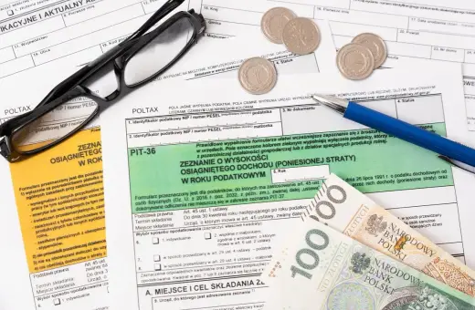 Okulary, długopis i pieniądze leżą na dokumentach podatkowych. Zastanawiasz się, co można odliczyć w PIT?
