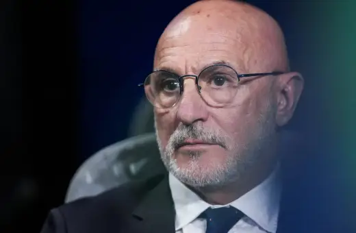 Łysy mężczyzna w okularach, z siwą brodą, w garniturze i krawacie. To trener reprezentacji Hiszpanii.