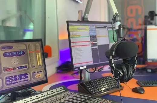 W studiu radiowym, gdzie słychać muzykę z **radio eska2 online**, wiszą słuchawki. Na monitorach widać zegar i program radiowy.