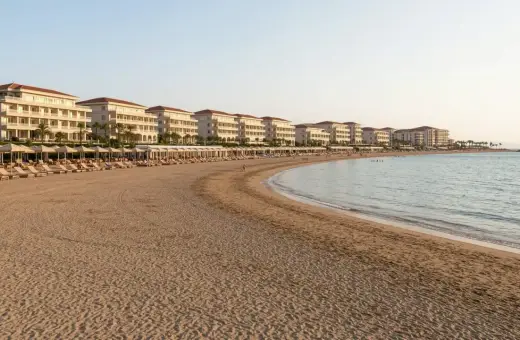 Piękna plaża z rzędami leżaków i białymi hotelami w tle, idealne miejsce na wakacje w Side Colakli.
