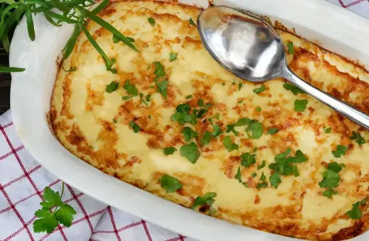 En gyllene omelett i ugn, toppad med färsk persilja och en sked redo att servera. Perfekt för en mysig frukost eller lätt lunch.