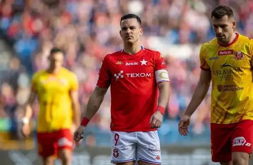 Piłkarze Wisły Kraków i Znicza Pruszków na boisku. W czerwonych strojach zawodnicy Wisły, w żółtych Znicza.