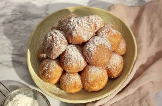 Stosik pysznych, puszystych pączków posypanych cukrem pudrem. Idealne na tłusty czwartek, te fit pączki wyglądają apetycznie.
