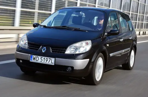 Czarny Renault Scenic 2 1.6 16v jedzie autostradą. Kierowca w okularach przeciwsłonecznych prowadzi auto.