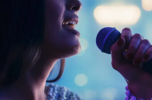 Kobieta śpiewa do mikrofonu, jej głos rozbrzmiewa w rytm muzyki. To idealny moment na playback.