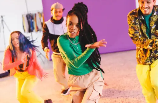 Grupa młodych ludzi tańczy w rytm muzyki dancehall. Energetyczne ruchy i kolorowe stroje tworzą radosną atmosferę.