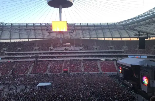 Tłum ludzi na koncercie na Stadionie Narodowym. Widok z góry na scenę i trybuny. Może to jedne z najgorszych miejsc na stadionie narodowym, bo daleko od sceny.