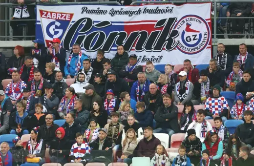 Tłum kibiców Górnika Zabrze, w szalikach i barwach klubowych, wspiera drużynę.