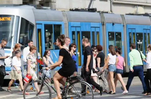 Ludzie przechodzą przez pasy, obok tramwaju z napisem "79 POŚWIETNE". To typowy widok wrocławskiego kod boczny pojazdu.