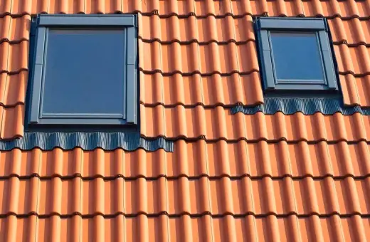 Dwa małe okienka w dachu z dachówki ceramicznej.