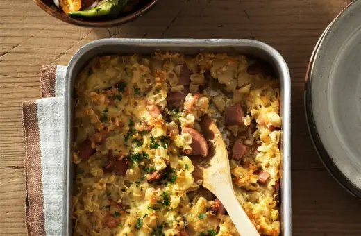 En gyllene makaronilåda med korv, toppad med persilja, redo att serveras. En klassisk svensk rätt som värmer själen.
