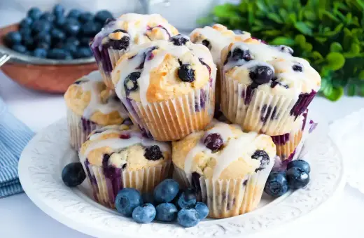 Wilgotne i puszyste muffinki z jagodami, polane lukrem. Idealne na śniadanie lub deser.