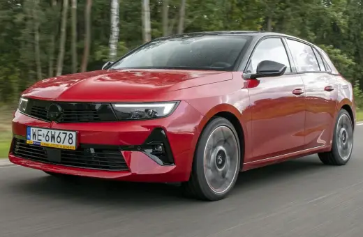 Czerwony Opel Astra Turbo pędzi leśną drogą.