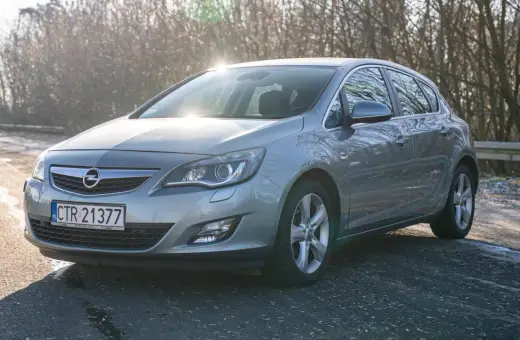 Szary Opel Astra z silnikiem 1.7 cdti zaparkowany na poboczu drogi, w tle drzewa i słońce.
