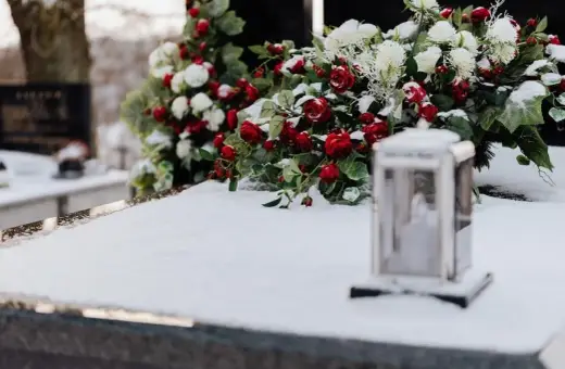 Wieniec dla taty: czerwone róże i białe kwiaty na śniegu, obok lampion.