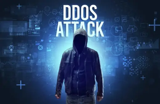 Anonimowa postać w kapturze na tle cyfrowych danych. Wielki napis "DDOS ATTACK" wyjaśnia, ddos co to.