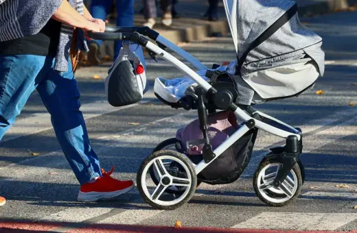 Rodzic z wózkiem, marzy o 1000 zł na drugie dziecko. Spacer po pasach, słońce i nadzieja na wsparcie.
