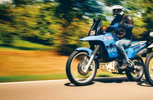 Motocyklista na niebieskim Suzuki DR 800 Big pędzi po drodze. Poznaj suzuki dr 800 big dane techniczne i poczuj wolność.