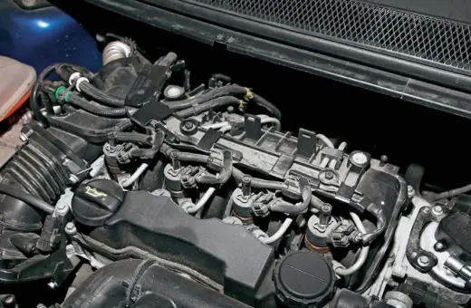 Silnik Volvo V50 1.6 diesel z widocznymi wtryskiwaczami, przewodami i zbiorniczkiem płynu chłodniczego.