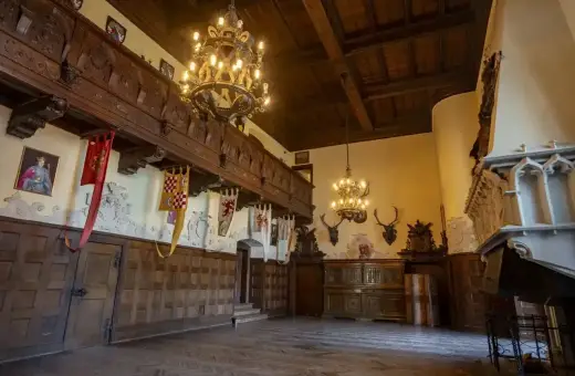 Wnętrze zamku Czocha z bogatymi zdobieniami, portretem króla i banerami. Bilety do zamku czekają na odkrycie jego historii.