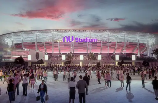 Tłum kibiców zmierza na mecz do Inter Miami Stadium. Zachodzące słońce maluje niebo na różowo, a stadion lśni w różowych barwach.