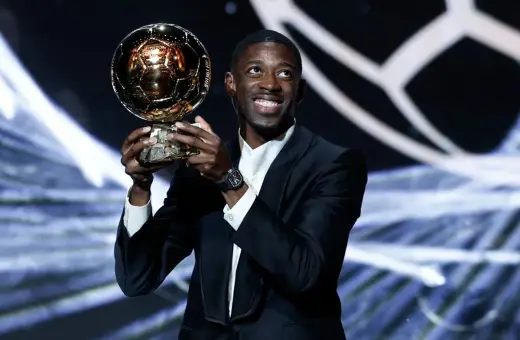 Piłkarz Ousmane Dembélé trzyma Złotą Piłkę na scenie.