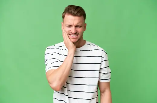 Mężczyzna z bólem zęba, zastanawia się, ile trzyma znieczulenie po wyrwaniu 8.